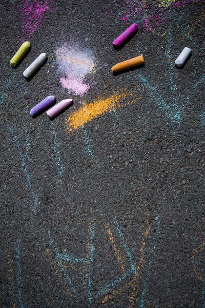 Colorful childrens crayons on asphalt, background, close up