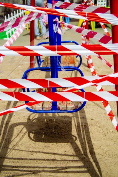 Dangerous childrens swings are wrapped in a white-and-white warning tape. — Stock Photo, Image