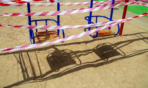 Dangerous childrens swings are wrapped in a white-and-white warn — Stock Photo, Image