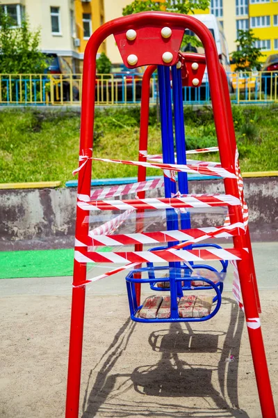 Dangerous childrens swings are wrapped in a white-and-white warning tape. — Stock Photo, Image