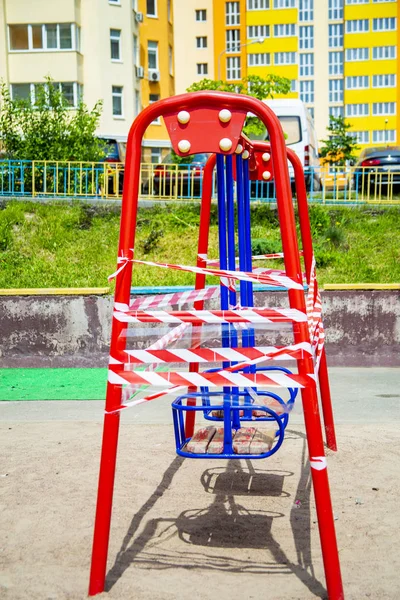 Dangerous childrens swings are wrapped in a white-and-white warning tape. — Stock Photo, Image