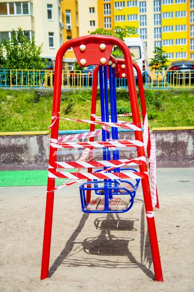 Dangerous childrens swings are wrapped in a white-and-white warning tape. — Stock Photo, Image