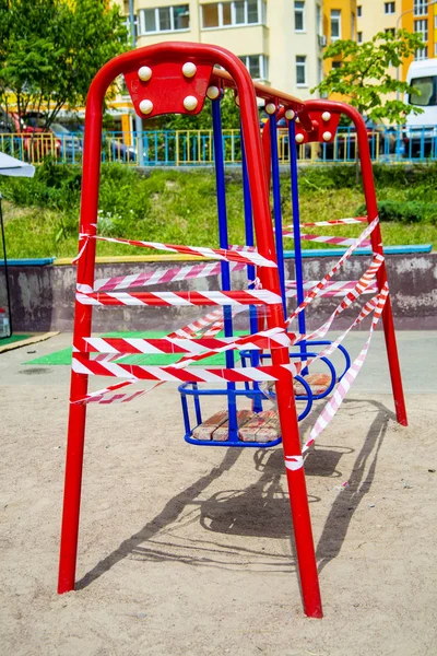 Dangerous childrens swings are wrapped in a white-and-white warning tape. — Stock Photo, Image