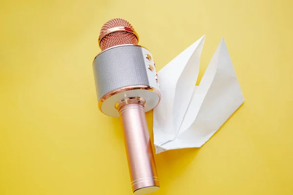 Micrófono de karaoke portátil rosa plateado para niños y papel blanco Swan-origami sobre fondo amarillo brillante — Foto de Stock