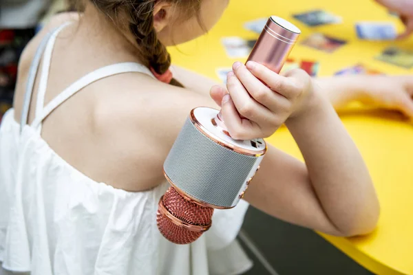 La mano dei bambini tiene un portatile per bambini microfono karaoke colore rosa-argento — Foto Stock