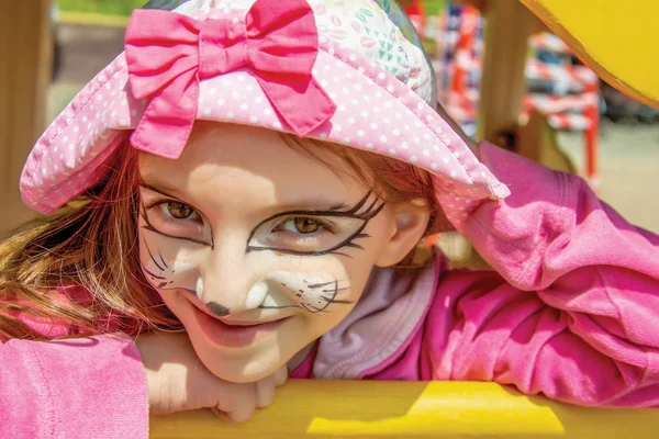 Portret van meisje in roze kleding met een kitten gezicht schilderen — Stockfoto