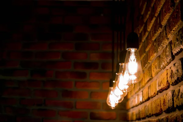 Uma linha de lâmpadas retro queimando perto de uma parede de tijolo, vintage — Fotografia de Stock