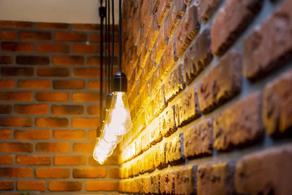 Uma linha de lâmpadas retro queimando perto de uma parede de tijolo, vintage — Fotografia de Stock