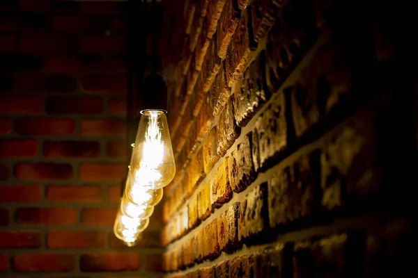 Une rangée d'ampoules rétro brûlantes près d'un mur de briques, vintage — Photo
