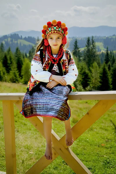 A pretty girl in an old national Ukrainian costume on a background of a mountain green landscape on a sunny day — Stock Photo, Image