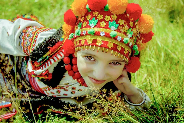 Girl in an old national Ukrainian costume lies on green grass on a sunny day — Stock Photo, Image