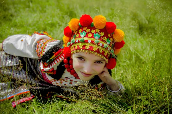 Flicka i en gammal nationell ukrainsk kostym ligger på grönt gräs på en solig dag — Stockfoto