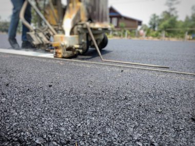 Teknisyenler asfalt yüzeyinde ki trafik hatları üzerinde çalışıyor.