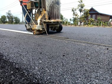 Teknisyenler asfalt yüzeyinde ki trafik hatları üzerinde çalışıyor.