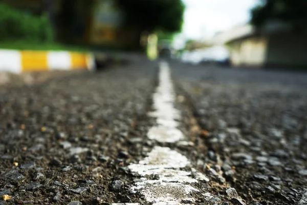 La carretera pavimentada tiene líneas de tráfico blancas en la superficie. Borrosa b — Foto de Stock