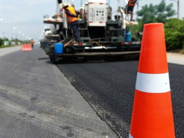 ASPHALT HOT MIX IN - Place RECYCLING metodu ve önünde kırmızı bir koni ile yol bakımı (bulanık resim).