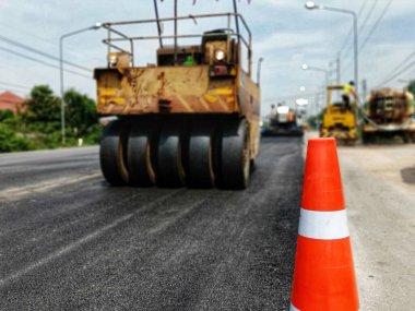 ASPHALT HOT MIX IN - Place RECYCLING metodu ve önünde kırmızı bir koni ile yol bakımı (bulanık resim).