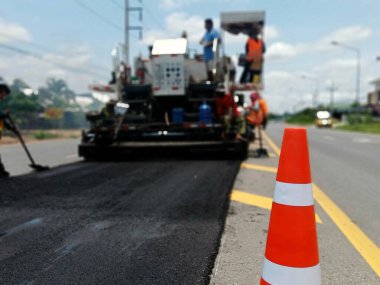 ASPHALT HOT MIX IN - Place RECYCLING metodu ve önünde kırmızı bir koni ile yol bakımı (bulanık resim).