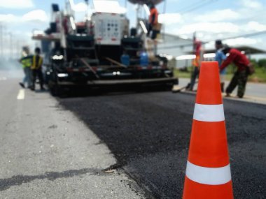 ASPHALT HOT MIX IN - Place RECYCLING metodu ve önünde kırmızı bir koni ile yol bakımı (bulanık resim).