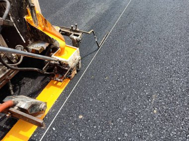 İşçiler çalışıyor. Tayland 'da güvenli yol güvenliği için sarı bir trafik çizgisi çekin.