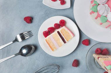 Bir parça ahududulu kek tabağı ve ahududu.