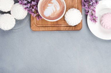 Leylak, kahve ve latte tablosu, gri ahşap masa. Romantik bir sabah. Yat yere.