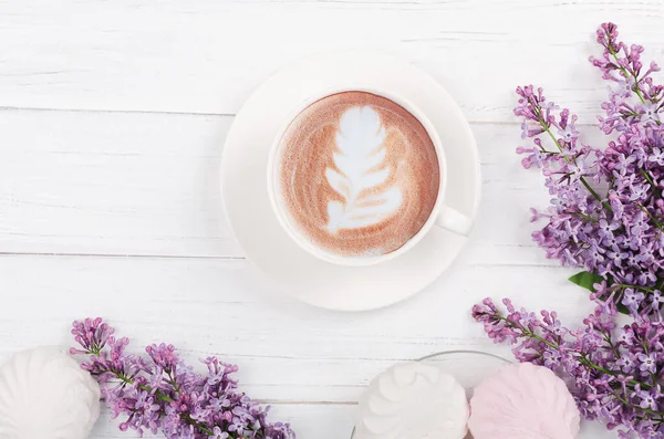 Lilás, café com arte latte sobre mesa de madeira clara. Manhã romântica.Flat lay — Fotografia de Stock