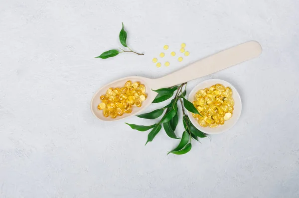 Yellow pills on wooden spoon on light background — Stock Photo, Image