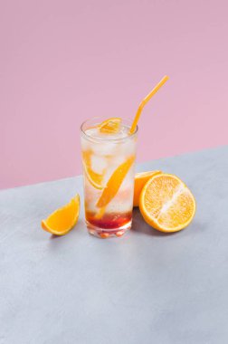 Pembe ve gri arka planda turuncu meyve dilimli turuncu alkol kokteyli.