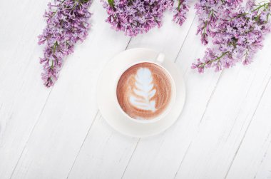 Leylak, açık ahşap masa üzerinde latte sanat ile kahve. Romantik bir sabah. Düz yatıyordu