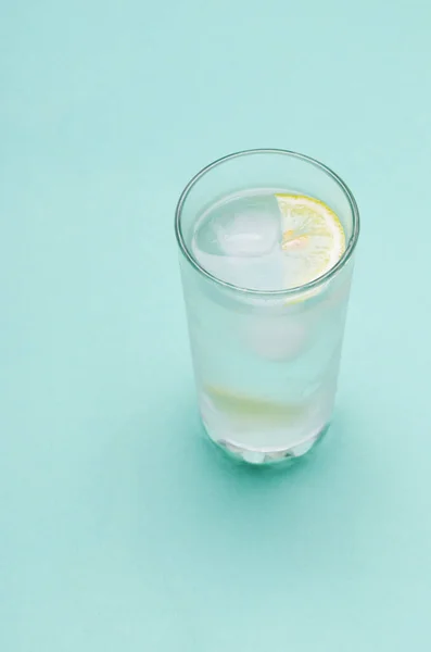 Cocktail with ice and lemon slice on blue background — Stock Photo, Image