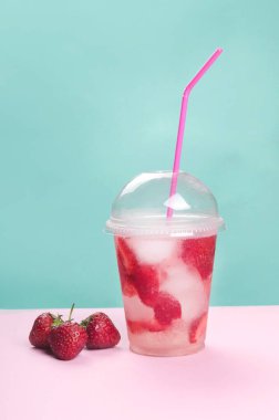 Pembe ve yeşil arka planda çilekli kokteyl.
