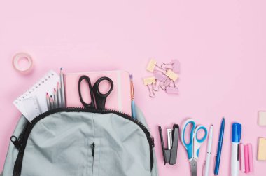 Açık pembe arka planda farklı okul malzemeleri