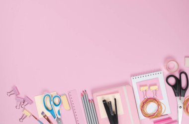 Pembe arka planda farklı okul malzemeleri.