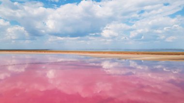 Renkli pembe tuz gölü ve bulutların yansıması.