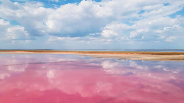 Renkli pembe tuz gölü ve bulutların yansıması.