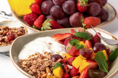 Meyve salatası yoğurt ve granola tatlı sağlıklı kahvaltı için berry. Üzüm, srtawberry, mango ve turuncu ile plaka