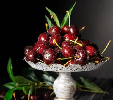 Dekoratif bir stand, koyu ahşap arka plan kopya alanı ile taze kiraz. Yaz ve hasat kavramı. Kiraz makro. Vegan, Vejetaryen, çiğ gıda