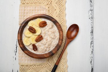 Beyaz ahşap masa günü kahvaltıda muz ve pekan fındık ile yulaf lapası
