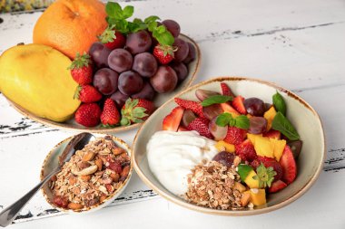 Meyve salatası yoğurt ve granola tatlı sağlıklı kahvaltı için berry. Üzüm, srtawberry, mango ve turuncu ile plaka