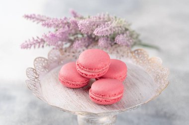 Pembe macaroons vintage bir tabak ve çiçekler. Pastel renkli