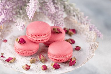 Pembe macaroons vintage bir tabak ve kurutulmuş çiçek tomurcukları. Pastel renkli