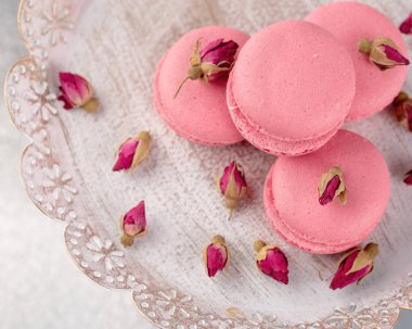 Pembe macaroons vintage bir tabak ve kurutulmuş çiçek tomurcukları. Pastel renkli