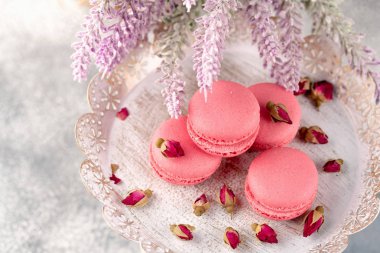 Pembe macaroons vintage bir tabak ve kurutulmuş çiçek tomurcukları. Pastel renkli