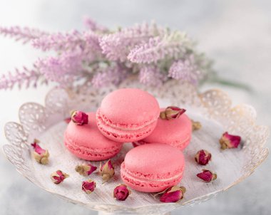 Pembe macaroons vintage bir tabak ve kurutulmuş çiçek tomurcukları. Pastel renkli
