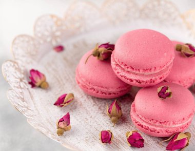 Pembe macaroons vintage bir tabak ve kurutulmuş çiçek tomurcukları. Pastel renkli
