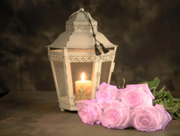 Beautiful white roses and candle on table against black backgrou