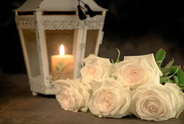 Rosas brancas bonitas e vela na mesa contra backgrou preto — Fotografia de Stock