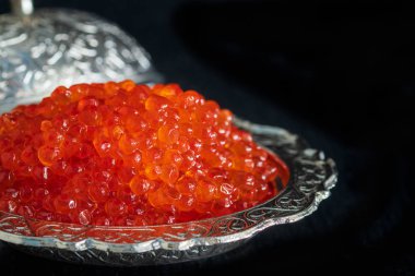 Siyah arka plan üzerinde gümüş kase kırmızı havyar