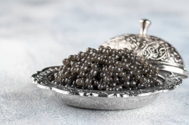 Açık arka planda gümüş kase siyah havyar